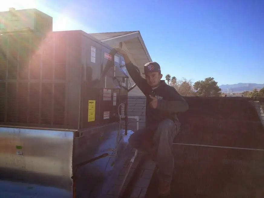 HVAC technician performing AC Tune-Up on a rooftop unit in Henderson